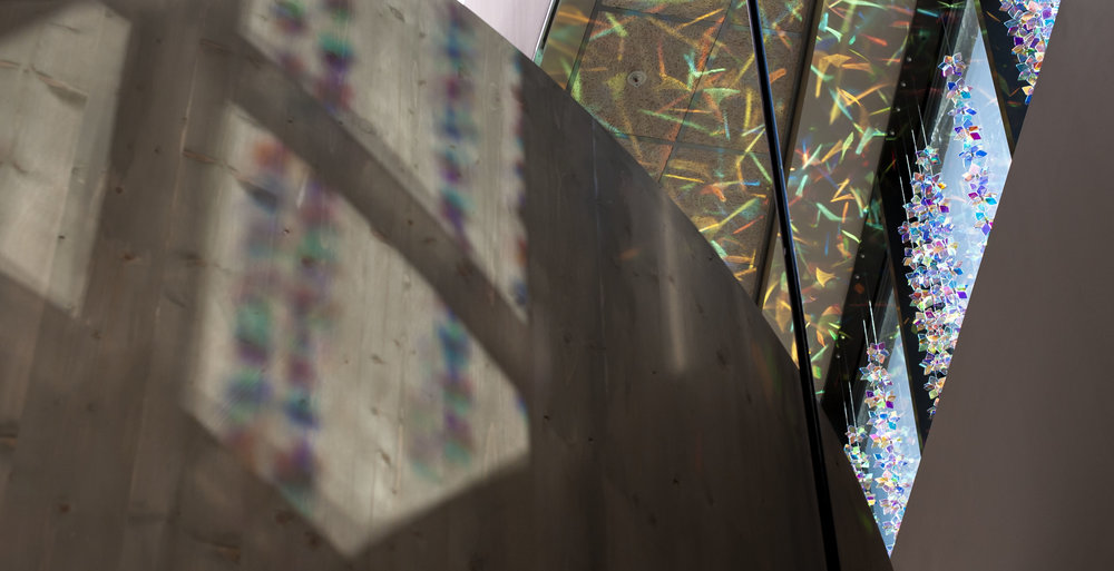 opllyse instalacion de cristales de colores suspendidas junto a los ventanales 