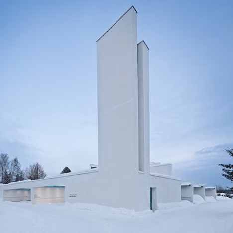 Capilla de St. Lawrence de Avanto Architects en Finlandia, torre blanca y volumen bajo sobre la nieve