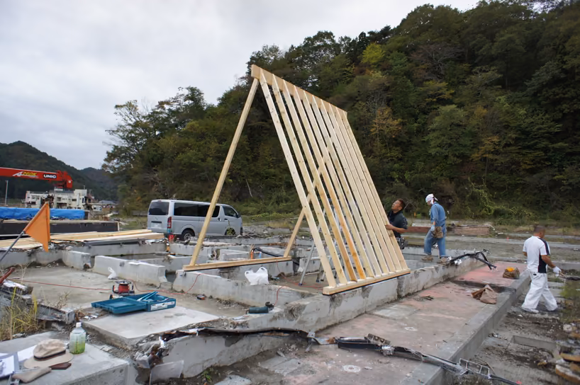 proceso de construcción Construcción del refugio Gassho: armazón triangular de madera sobre losas de hormigón con operarios