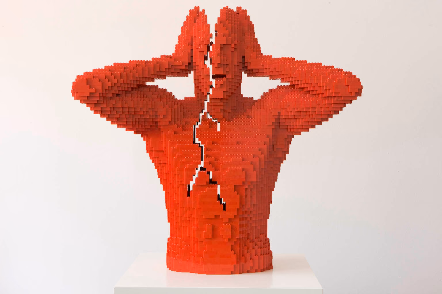 Escultura de LEGO rojo de Nathan Sawaya: torso con las manos en la cabeza y una grieta en el pecho