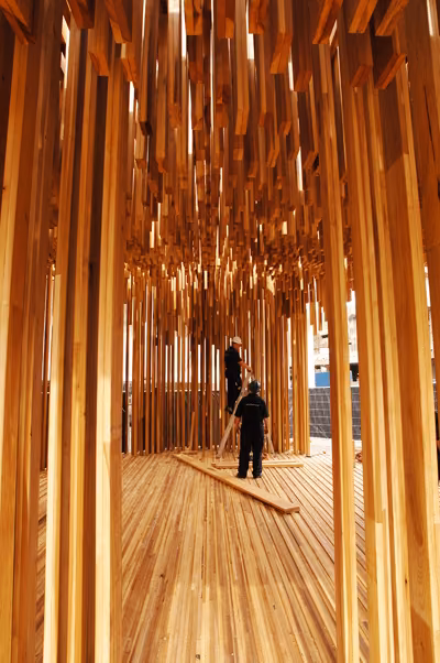 interior Interior del pabellón Sclera de Adjaye con listones de madera colgantes y dos personas dentro
