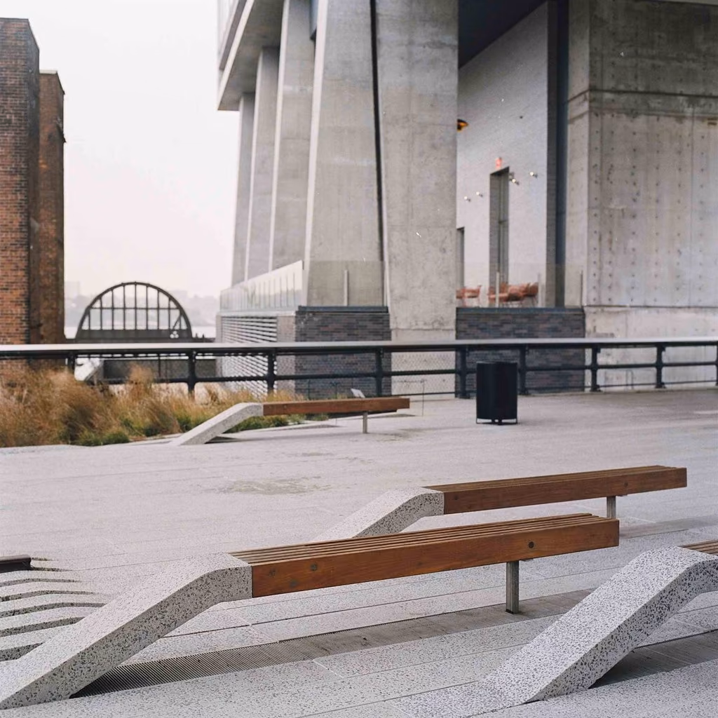 Bancos de madera y pavimento de hormigón bajo un edificio en el parque High Line de Nueva York