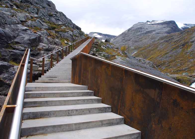escalera Escalera de hormigón con barandilla de acero corten subiendo entre montañas en el mirador de Trollstigen