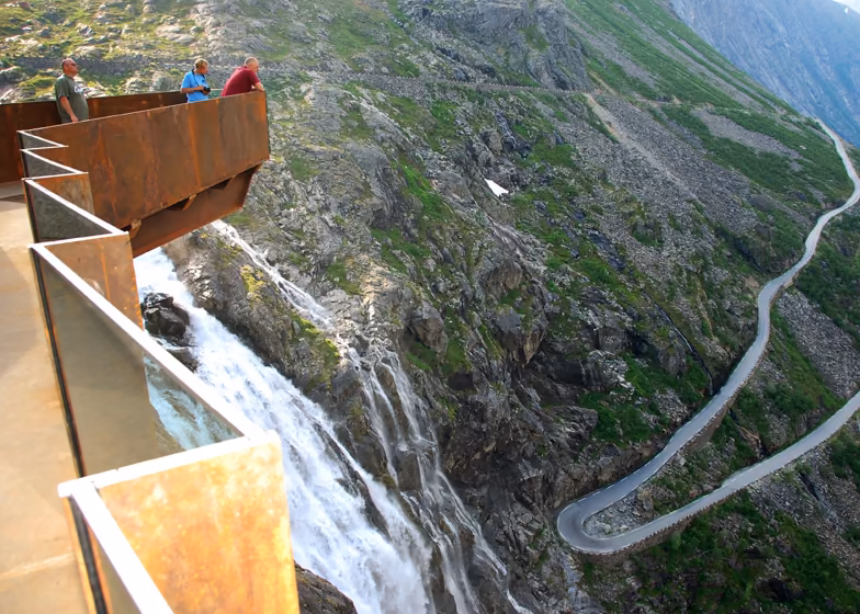 mirador Visitantes en un mirador de acero corten y vidrio sobre una cascada y la carretera en zigzag de Trollstigen
