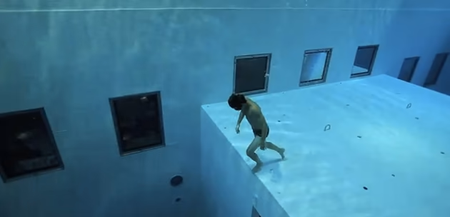 Buceador sobre una plataforma sumergida con ventanas de observación en las paredes de NEMO 33