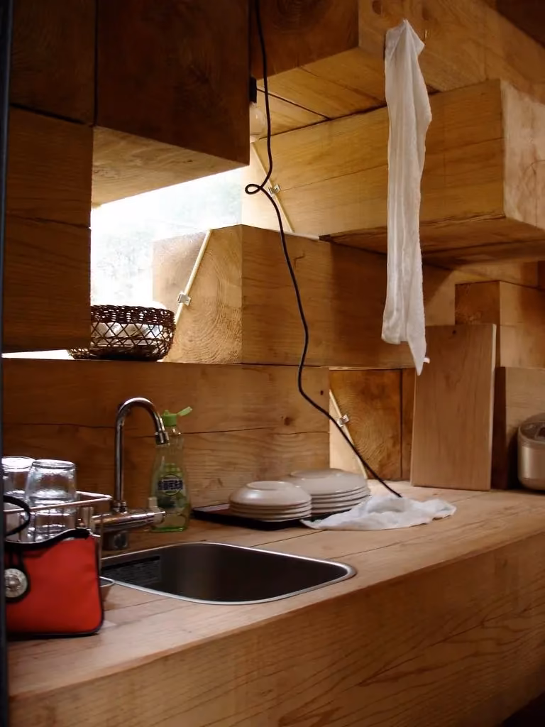 fregadero Fregadero encajado entre bloques de cedro apilados en la Casa de Madera de Sou Fujimoto