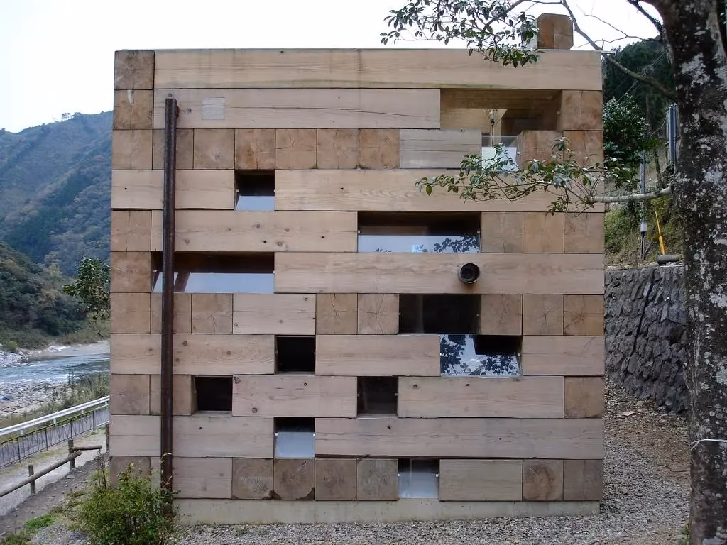 fachada Fachada de bloques de cedro apilados con huecos acristalados de la Casa de Madera junto a un río