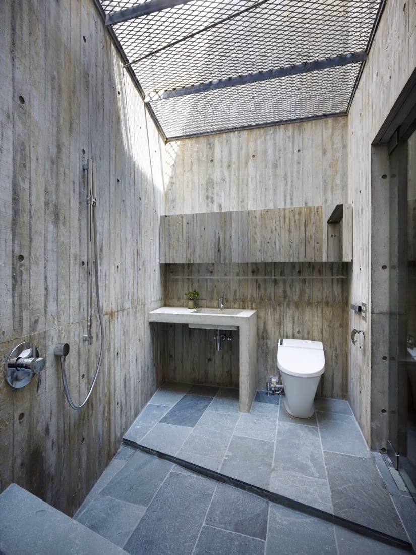 baño Baño de hormigón encofrado con suelo de pizarra y cubierta de rejilla abierta al cielo en la Casa Hiro