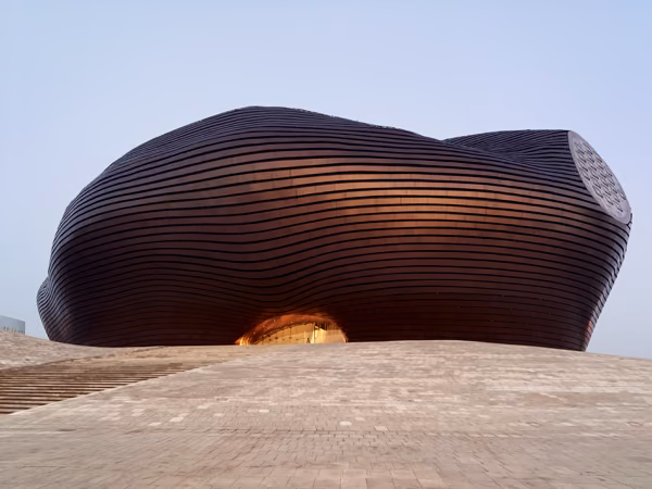 ordos3 Volumen redondeado de lamas broncíneas del Museo Ordos sobre una base de piedra, con la entrada iluminada