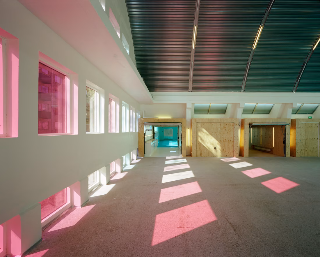 Nave de paredes blancas con ventanas rosas que proyectan luz sobre el suelo, en el centro SJA