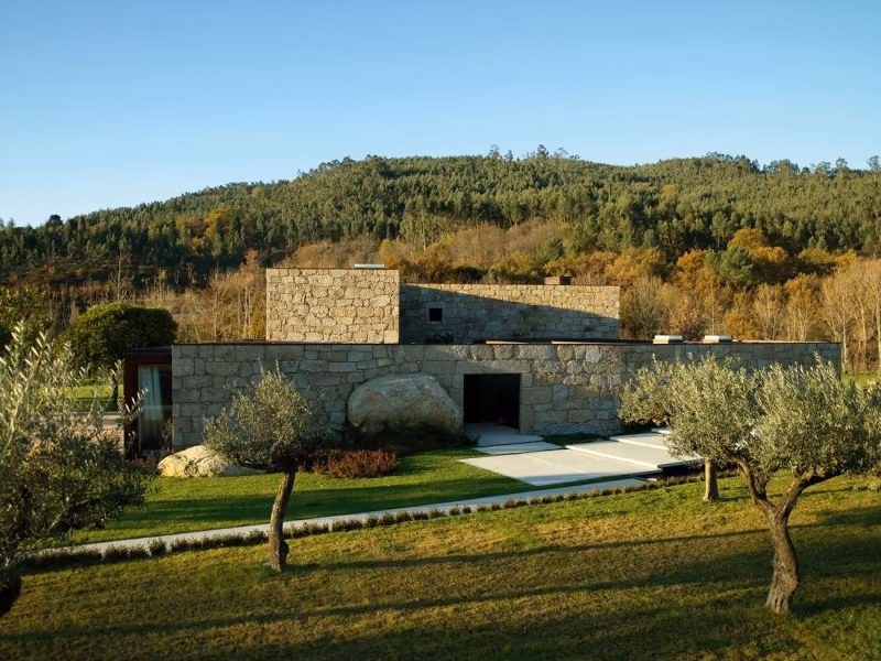general2 Granja reformada en Brito por Topos Atelier, de muros de granito entre olivos y césped con monte boscoso detrás