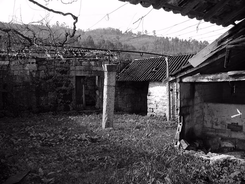 antes Patio de la granja de Brito antes de la reforma, con construcciones de piedra en ruinas y tejados de chapa