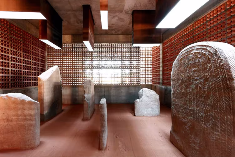 Interior del espacio del dolmen de Seró de Toni Gironés: piedras megalíticas bajo un techo de celosía cerámica