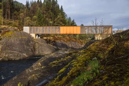 Puente Hose de acero corten y madera salvando un cauce entre rocas cubiertas de musgo en el bosque noruego