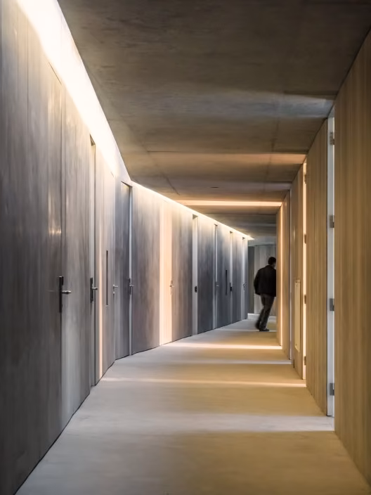 Pasillo de hormigón y madera con luz indirecta que recorre las habitaciones del Centro de Alto Rendimiento de Remo