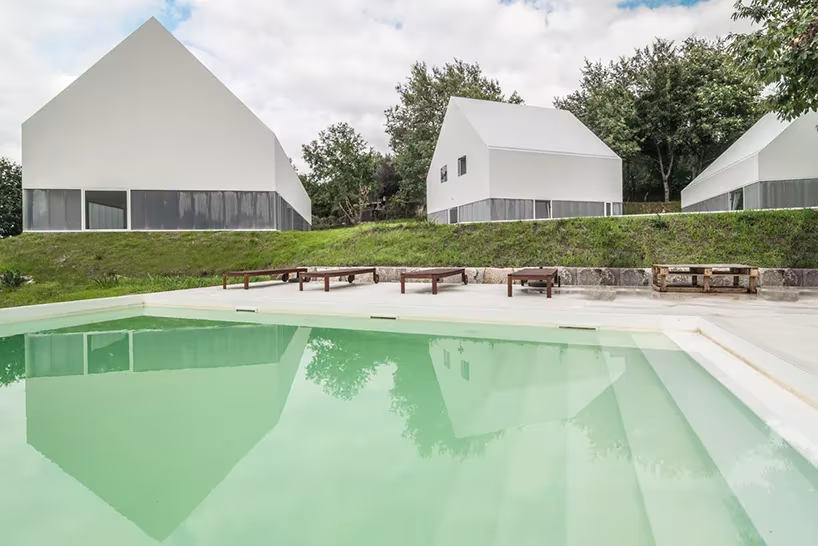 White Wolf Hotel de AND-RÉ en Penafiel: casas blancas a dos aguas reflejadas en la piscina verde