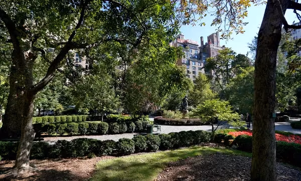 Jardín arbolado de Gramercy Park, el parque privado de Manhattan, con setos recortados y edificios al fondo