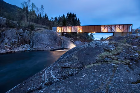 Puente Hose iluminado al anochecer sobre el río y las rocas, con el valle noruego al fondo