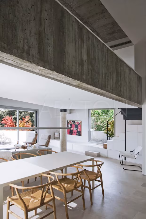 CASA 36-8 Comedor con sillas de madera bajo una viga de hormigón encofrado en el ático Casa 36 de Madrid