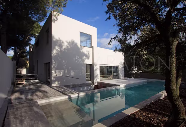 Oficina-6 Fachada blanca con terraza, árboles y piscina de la oficina-vivienda-showroom del estudio Ábaton
