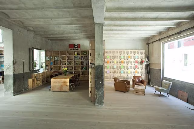 Antiguo garaje convertido en HUB Madrid, con techo de hormigón, pilar central, mesas de trabajo y estanterías