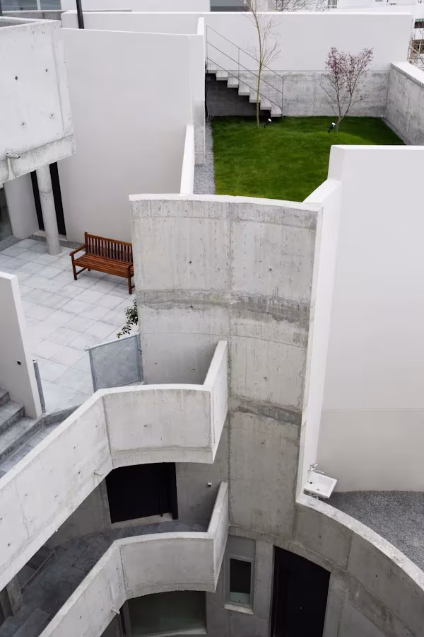 Patio de hormigón visto con escaleras y bancal de césped visto desde lo alto en una terraza ajardinada