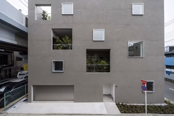 House K de K2YT Architects en Tokio, fachada gris con ventanas cuadradas dispersas y jardines interiores visibles
