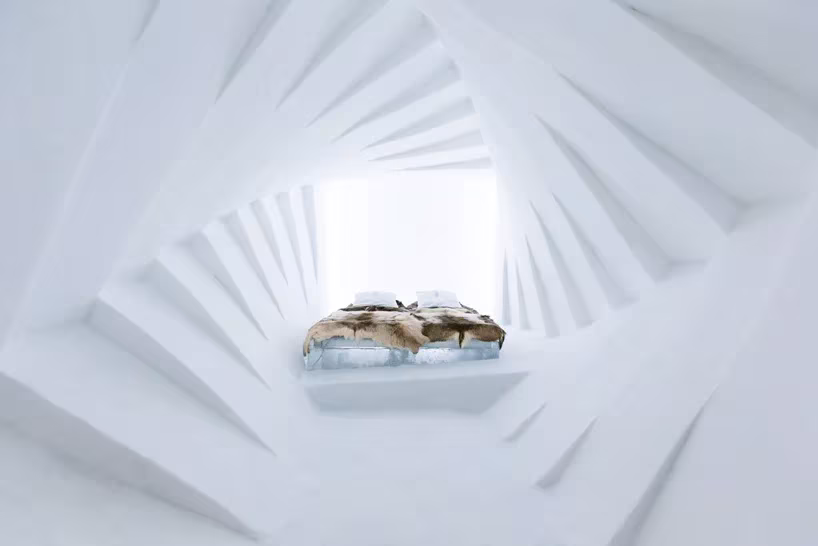 Habitación del Icehotel de Jukkasjärvi con paredes de hielo talladas en espiral y una cama cubierta de pieles
