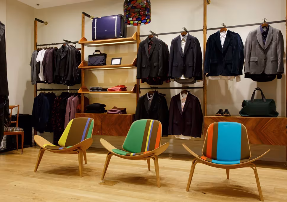 Butacas CH07 Shell de Wegner tapizadas con rayas de colores de Paul Smith en una tienda de ropa