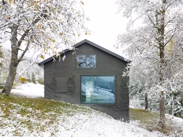 Mayen suizo rehabilitado por Savioz Fabrizzi, casa de piedra con gran ventana cuadrada en una ladera nevada