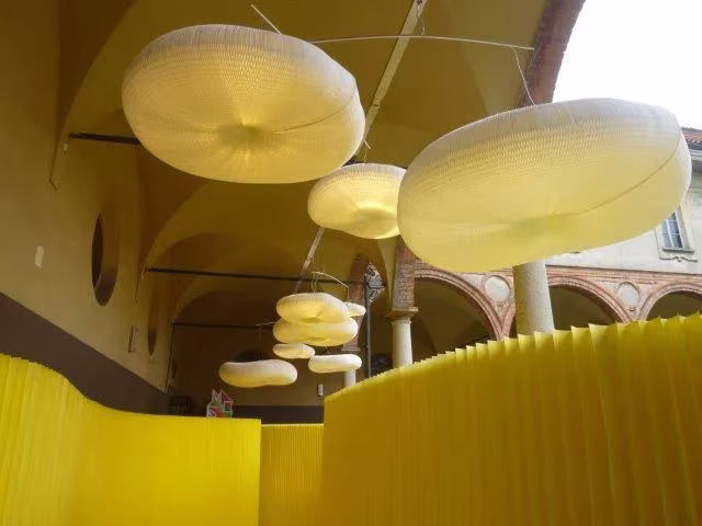 Lámparas blandas de Molo colgadas en un claustro con tabiques amarillos durante la Semana del Diseño de Milán