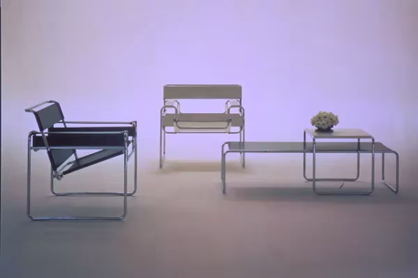 Sillas Wassily de Marcel Breuer en cuero negro y tubo de acero con mesas a juego sobre fondo lila