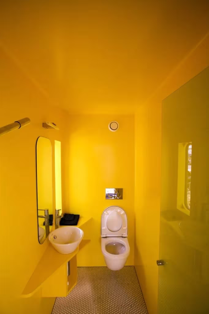 landscape28 Baño revestido íntegramente de amarillo, con lavabo ovalado e inodoro suspendido, en un proyecto de Molo