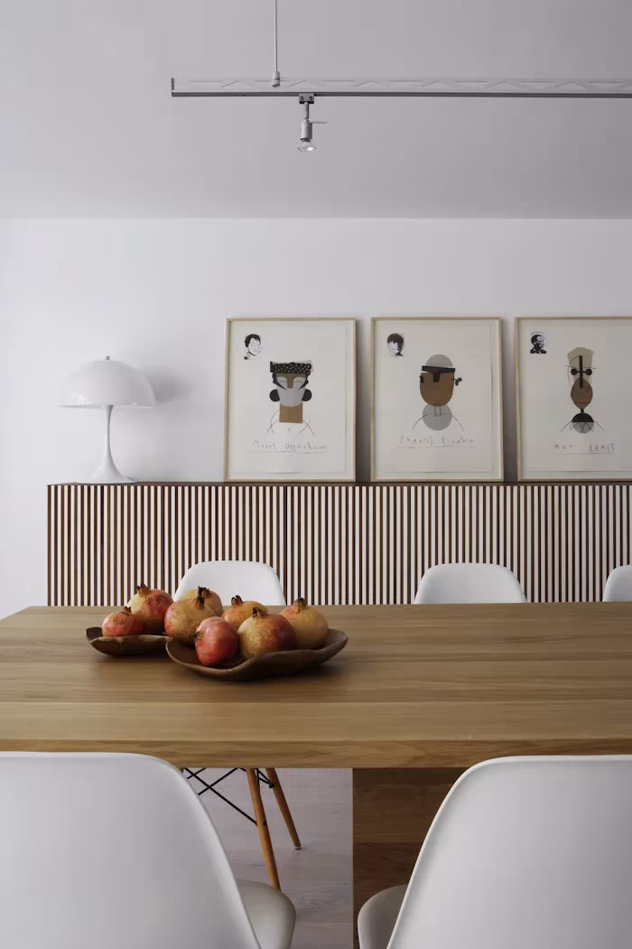 _X5C4761 Mesa de madera con frutero y sillas blancas ante un aparador de lamas y tres láminas enmarcadas en el Ático en U