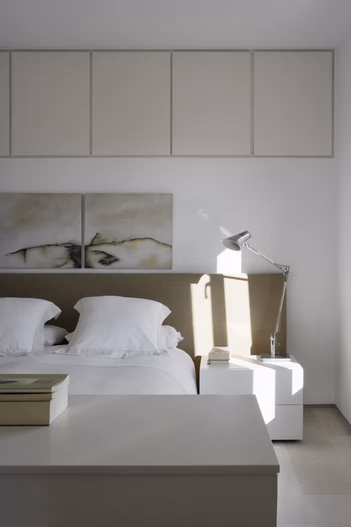 _X5C4885 Dormitorio blanco con cabecero beige, armarios altos y lámpara articulada en el Ático en U