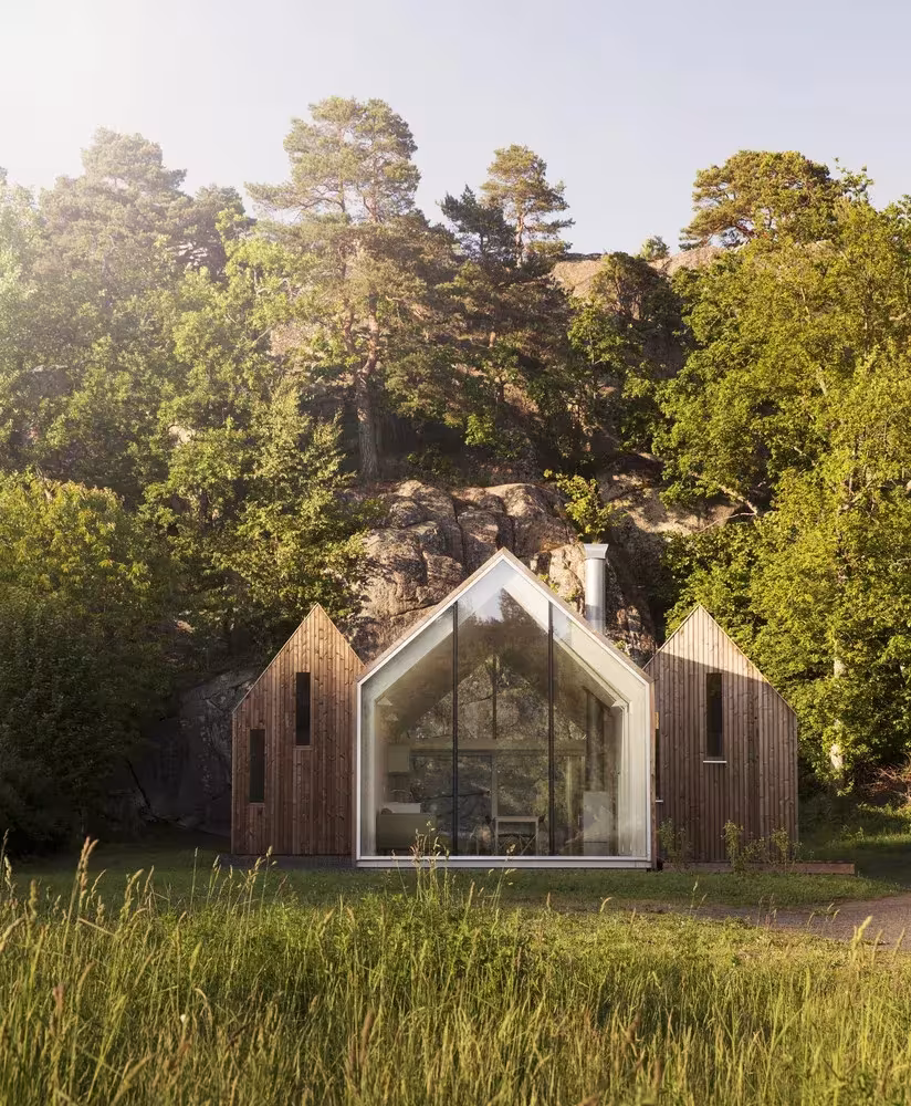 Cabaña de Reiulf Ramstad en Noruega, volúmenes de madera a dos aguas con fachada acristalada entre pinos y hierba alta