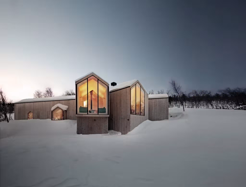 Split View Mountain Lodge de Reiulf Ramstad, con volúmenes de madera y grandes ventanales iluminados en la nieve