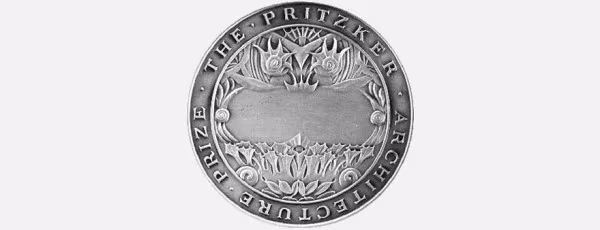 Medalla de bronce del Premio Pritzker de Arquitectura con su inscripción y relieve sobre fondo gris claro