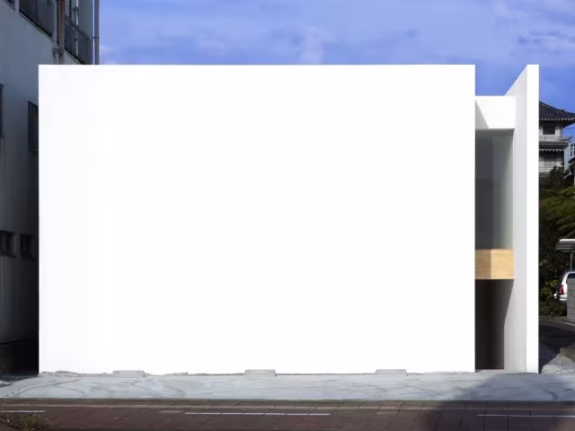 House-T en Miyazaki: gran muro blanco de hormigón que cierra la vivienda frente a la calle