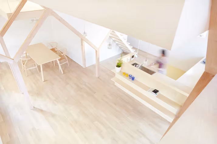 Cocina y comedor de la Casa H de Hiroyuki Shinozaki entre vigas de madera clara y suelo de tarima