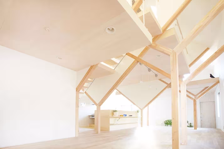 Planta baja diáfana de la Casa H con pilares de madera ramificados que sostienen los niveles superiores