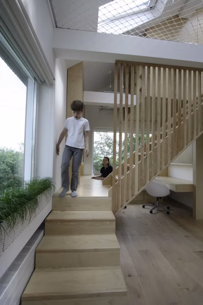 Dos niños en la escalera de madera clara y la zona de estudio de la residencia de Moscú