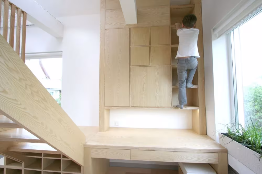 Niño trepando por un armario de madera que hace de escalera hacia el altillo de la residencia de Moscú