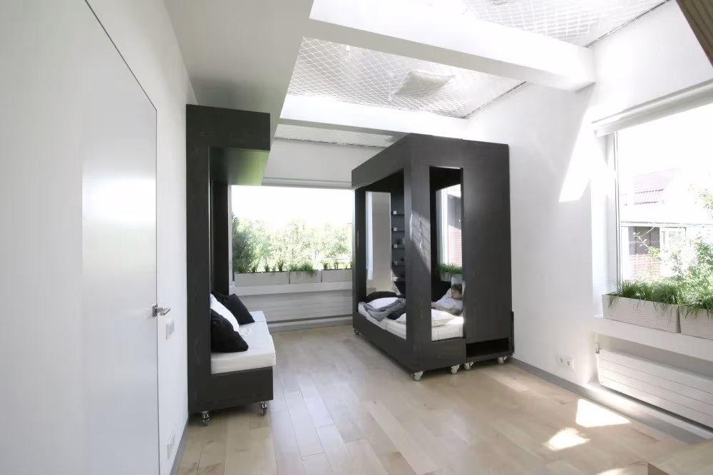 Módulos negros del cubo transformable abiertos como sofá y cama junto al ventanal del cuarto de Moscú