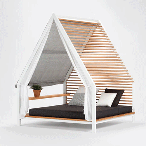 Cama Cottage de Kettal con lamas de madera y una tela gris a medio desplegar sobre el colchón negro