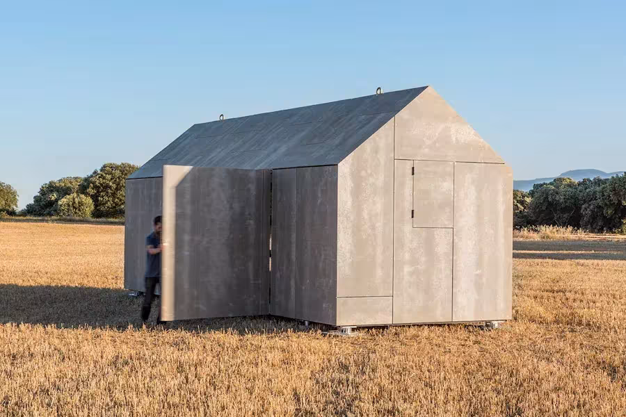 Casa Transportable ÁPH80 de ÁBATON con fachada gris de cubierta a dos aguas en un campo de rastrojo