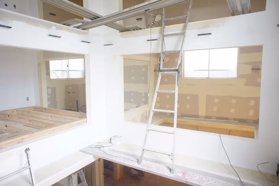 Obra de la House T con huecos entre niveles, tablero de madera y una escalera metálica apoyada