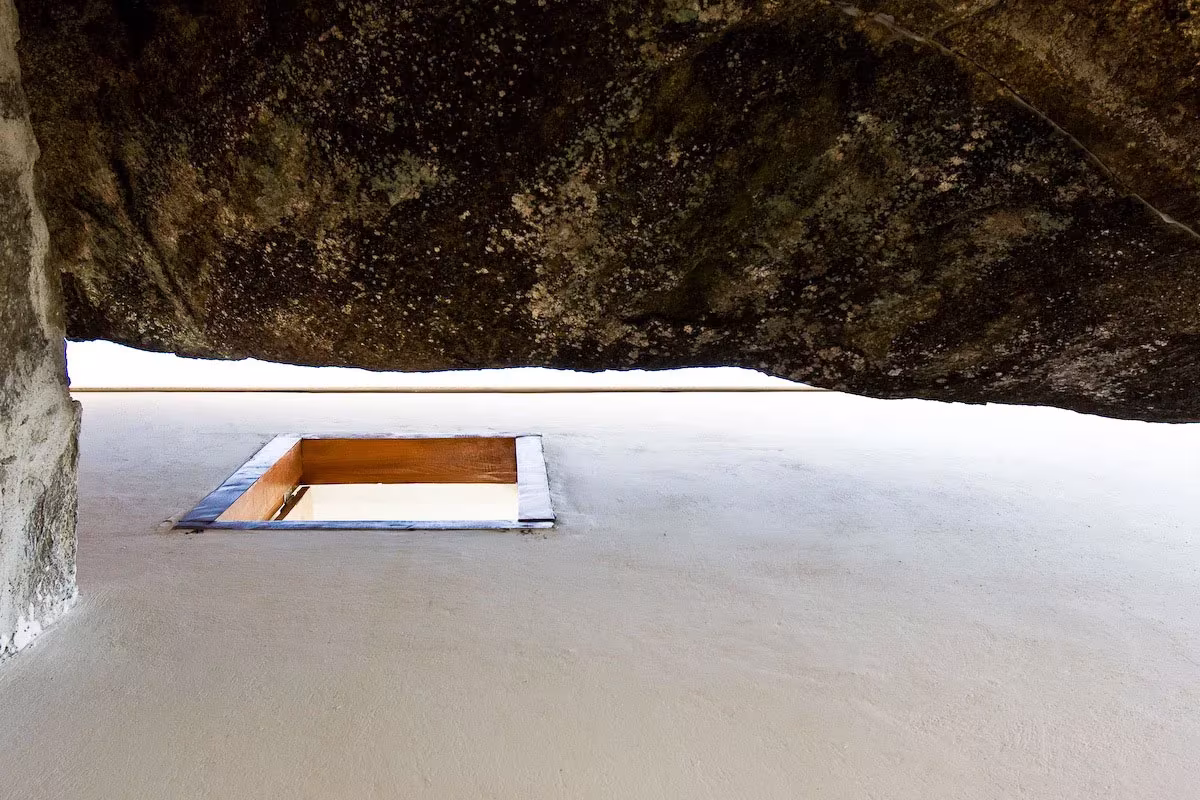 Lucernario cuadrado en una cubierta blanca bajo una gran roca en la Box House de una isla brasileña
