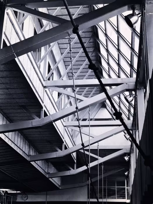 Lucernario y cerchas metálicas blancas del Gimnasio Maravillas vistos desde abajo, en blanco y negro