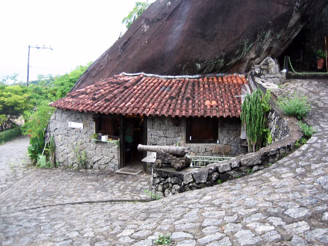 Casa original de piedra con tejado de teja árabe al pie de una gran roca, antes de la reforma de la Box House